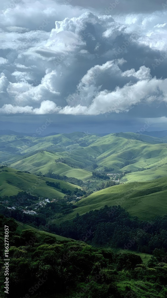 Obraz premium Emerald green rolling hills form a valley with a small village, beneath dramatic storm clouds. Concept Landscape Photography, Moody Skies, Village in a Valley, Rolling Hills, Dramatic Weather