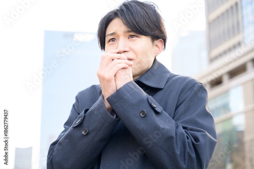 冬のオフィス街で寒そうな日本人男性