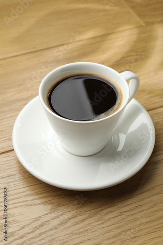 Aromatic coffee in cup on wooden table, closeup