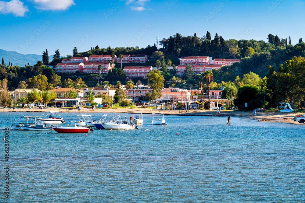 Obraz premium View Sidari Beach with tourists and boats on green holiday island Corfu, Greece. One the most beautiful islands in Ionian Sea.