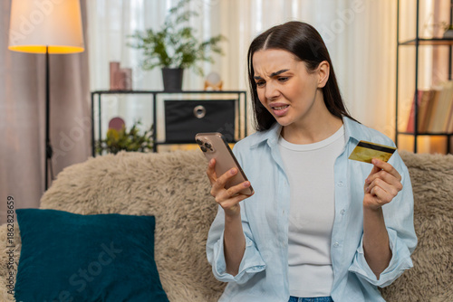 Bilde på lerret Young woman at home anxiously checking credit card balance on smartphone worried by blocked account or error