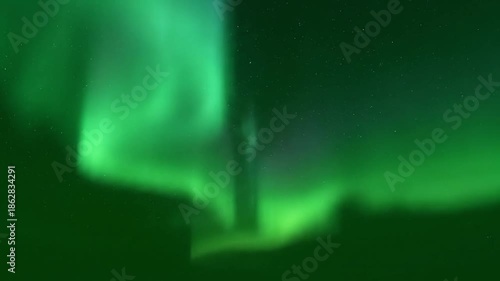 Ethereal green aurora borealis dances across a dark starry night sky.