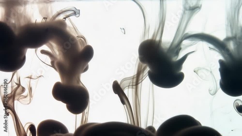 Brown ink swirling in water creating abstract shapes and patterns isolated on white background