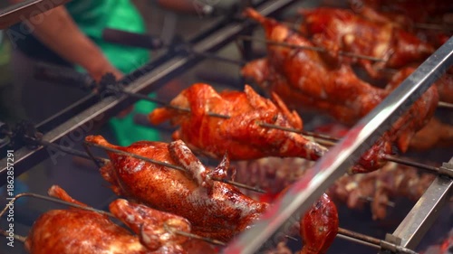 Wallpaper Mural A high-quality close-up shot of multiple whole ducks with golden, crispy skin rotating slowly on a mechanical rotisserie spit. Glistening fat, caramelized texture, and subtle wisps of smoke. Torontodigital.ca