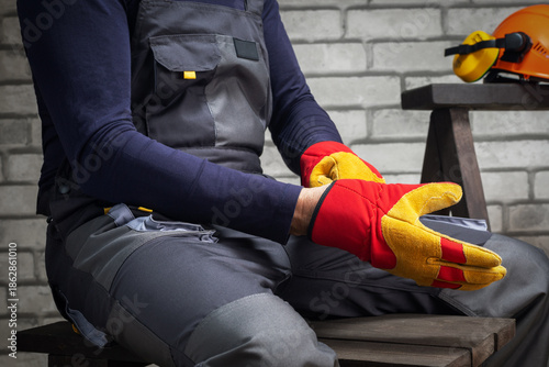 Close-up of construction worker putting on protective gloves. Concept safety equipment.
