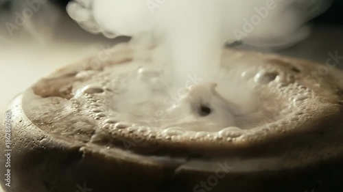 Steaming hot beverage in a cup with frothy foam and vapor rising