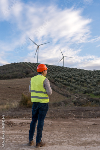 Engineer operating remote drone for wind turbine inspection, focusing on renewable energy and sustainable technology