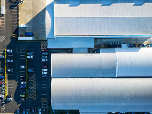 Interesting drop UAV view of a modern, metal clad factory and technology building in the UK. A part filed parking lot is on the right, used for employees.