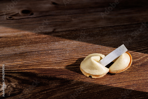 Billede på lærred Fortune cookies on a dark wooden table with black background for conceptual photography about mystery, predictions and future luck