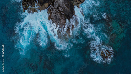 Coastal Pattern: Dark Boulders, White Foam, and Muted Teal Water Next to Island Villa