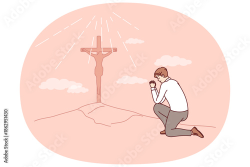 Businessman praying seeing christian cross on hill, worshiping lord and asking jesus for protection. Sunlight illuminates religious cross, to punish christian martyr who did not renounce religion