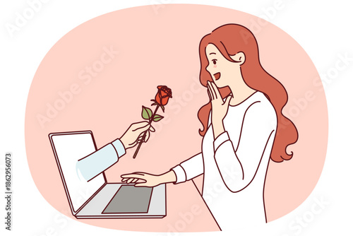 Gift flower from internet fan in laptop screen near enthusiastic woman using dating site. Overjoyed girl visits social networks and web dating apps for online flirting and finding boyfriend