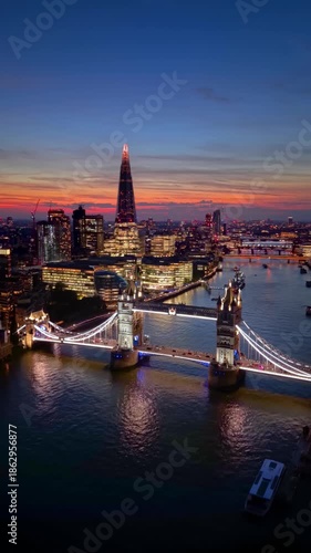 Aerial view of the illuminated Tower Bridge, River Thames and City skyscrapers in London, England, during dusk twilight
