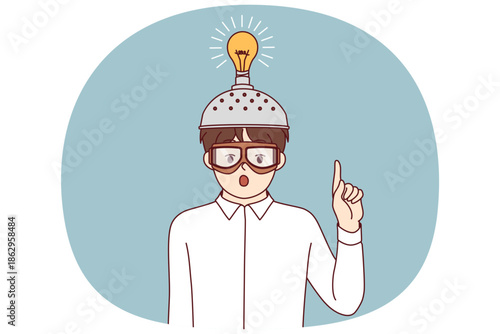 Inspired boy invented new idea and shows finger up standing with funny helmet with light bulb. Child inhabitant invented device to improve brain function and intellectual capabilities