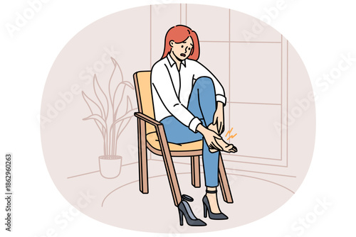 Woman with varicose veins feels pain in legs due to uncomfortable high-heeled shoes, sits on chair in apartment. Girl needs medicinal ointment to cure varicose veins or calluses on heel