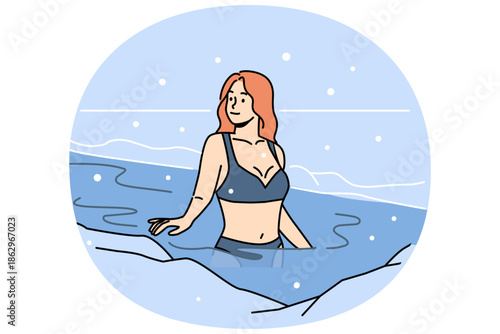 Woman bathes in ice hole on orthodox holiday of baptism, standing in icy water under falling snow. Girl undergoes baptism ritual to be killed and improve immunity or to receive blessing of lord