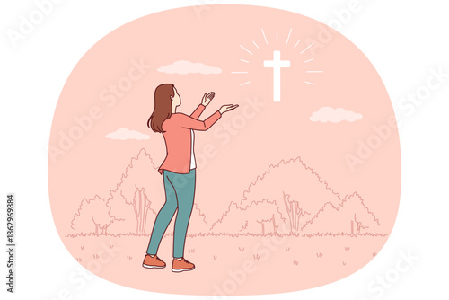 Catholic woman looks at cross glowing in sky, praying to god for help in finding right path. Sign from god in form of christian crucifix and believing girl looking in surprise at miracle