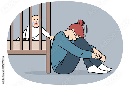 Exhausted mother with postpartum stress sits on floor near crib with crying newborn, and needs help of professional nanny. Postpartum stress in girl who does not pay attention to son
