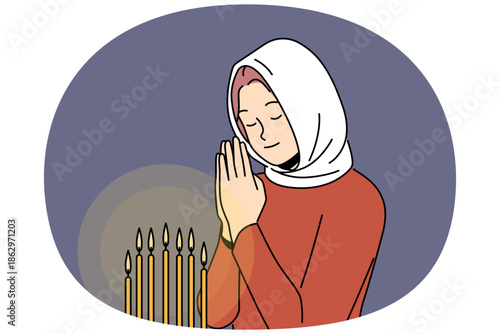 Praying woman stands in orthodox church near altar with candles and reads prayer, asking lord for help. Praying girl attends divine service to atone for sins or receive blessing of priest.
