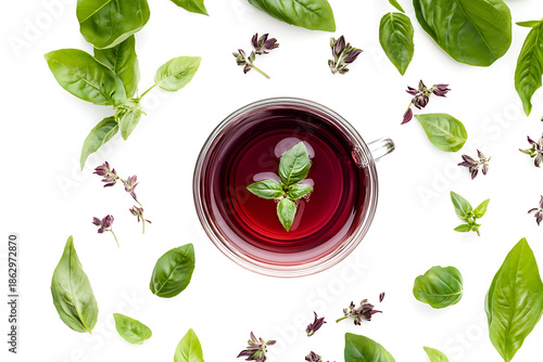 Vibrant herbal tea in a clear glass cup surrounded by fresh green leaves