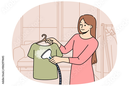 Woman housewife uses steam iron to treat clothes after washing and avoid wrinkles. Girl demonstrates work of steam iron, which simplifies housework or saves time and effort on routine activities.