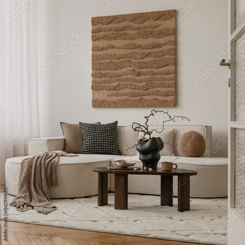 Earthy modern interior with round sofa, minimal coffee table, and large textured wall art in a soft natural palette.