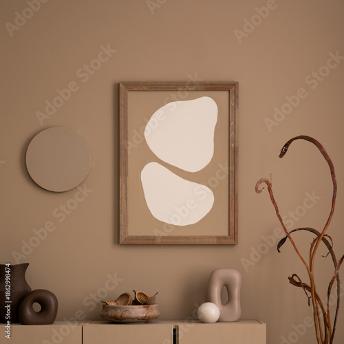 Creative composition of living room interior with mock up poster frame, brown sideboard, wooden coffee table, glass vase with branch , sculpture and personal accessories. Home decor. Template.