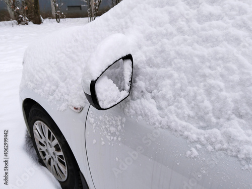 Snow covered car. Snowdrift on auto. Frozen side mirror. Stuck vehicle on off-road terrain in winter. Black ice. News for drivers. Snowy roads. Wheel. Ecology in city. Environment conversation.