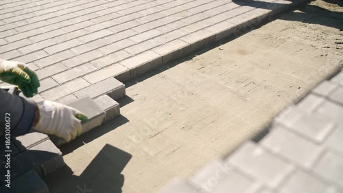 Laying gray interlocking brick pavers on a prepared sand base, creating a durable pavement for outdoor patio construction