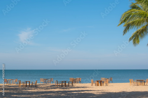 Sunny Tropical Beach Scene with Empty Wooden Dining Tables and Palm Trees