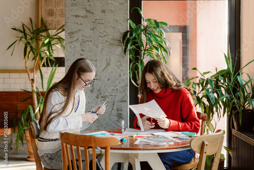 Quadro su tela Two girls joyfully engage in a crafting session at a sunlit table