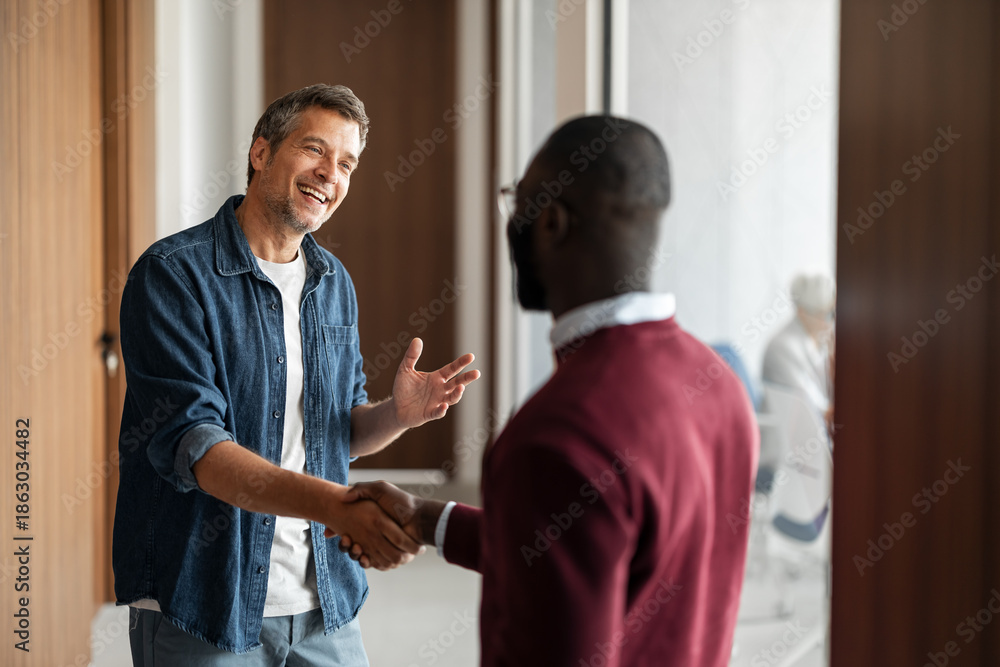 Obraz premium Friendly Handshake in Office Hallway Between Two Men, Warm Conversation and Teamwork Moment