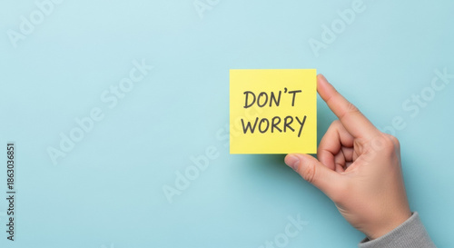 A hand holds a yellow sticky note with the words 