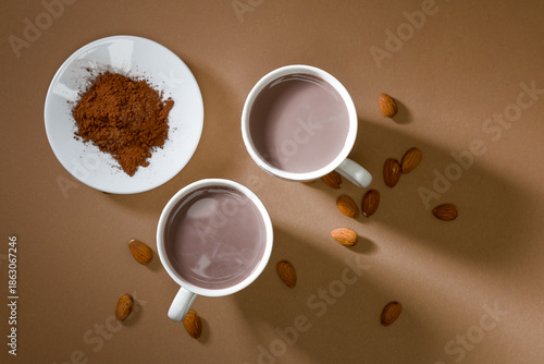 Hot drinks and cocoa powder with almonds on a brown background during a cozy afternoon gathering