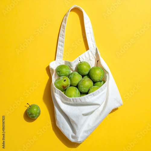 Wallpaper Mural Overhead shot of green plums in a white tote bag on bright yellow Torontodigital.ca