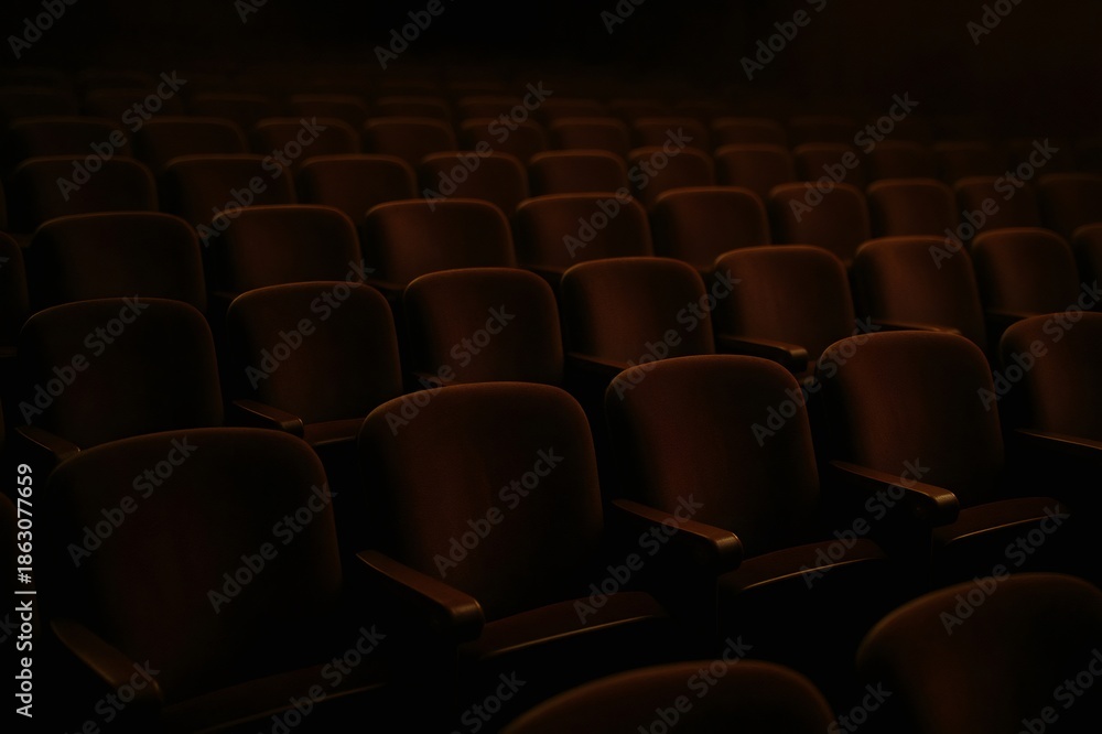 Fototapeta premium Rows of dark, unoccupied seats filling an auditorium, creating a tranquil atmosphere before an event or show begins