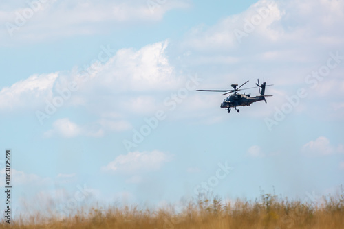 British army AH-64E Boeing Apache attack helicopter flying over Salisbury plain training area on a slight cloudy day
