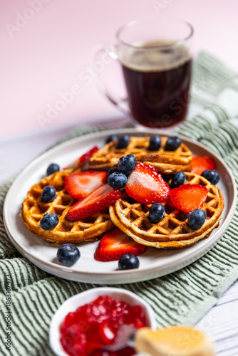 Waffles with strawberries and blueberries served with orange juice