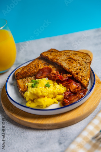 Scrambled eggs and bacon breakfast with toast and orange juice