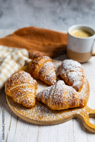 Fresh butter croissants on wooden board with coffee