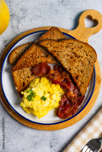 Scrambled eggs and bacon breakfast with toast and orange juice