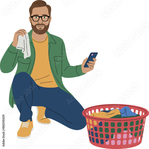 Man doing laundry at home, checking smartphone instructions, holding clothing, red basket of clothes, household chores, modern domestic lifestyle routine
