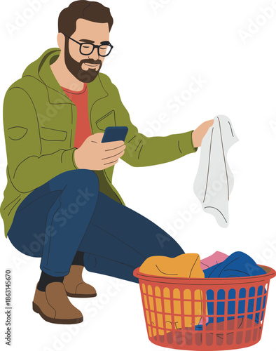 Man doing laundry at home, checking smartphone instructions, holding clothing, red basket of clothes, household chores, modern domestic lifestyle routine