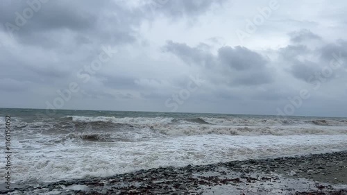 Dramatic ocean waves crashing on rocky beach under stormy skies