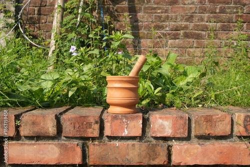 Terracotta Mortar and Pestle on a Rustic Brick Wall