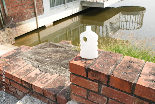Fotografi White Plastic Bottle on a Brick Wall by a Body of Water
