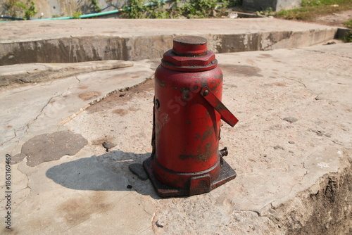 Red Hydraulic Bottle Jack on Concrete Surface