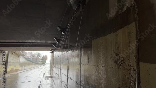 Rainwater stream flowing through urban tunnel illuminated by natural light