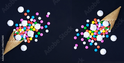 Ice cream cone with colored candy dragees and white meringue on the black background. Copy space. Top view.