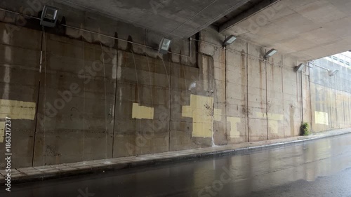 Urban underpass with rainsoaked pavement and reflections in soft subdued light